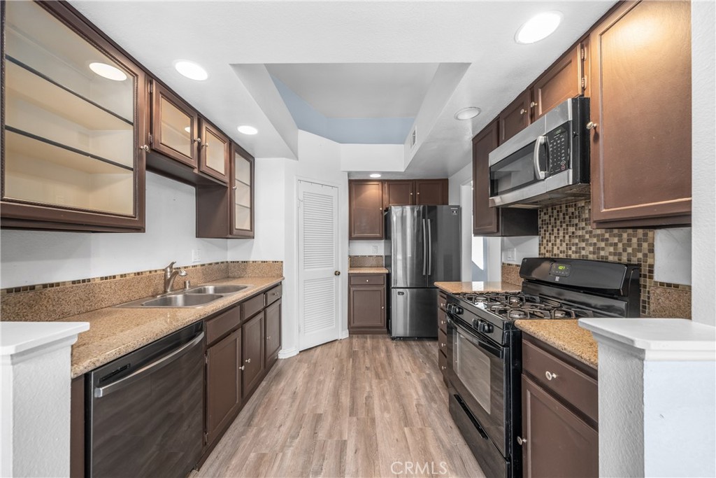 4900 North Grand Avenue, Unit 104 Covina, CA 91724 - Photo 11 of 27 a kitchen with stainless steel appliances granite countertop a stove a sink and a refrigerator