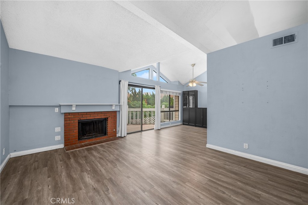 4900 North Grand Avenue, Unit 104 Covina, CA 91724 - Photo 15 of 27 an empty room with wooden floor fireplace and windows
