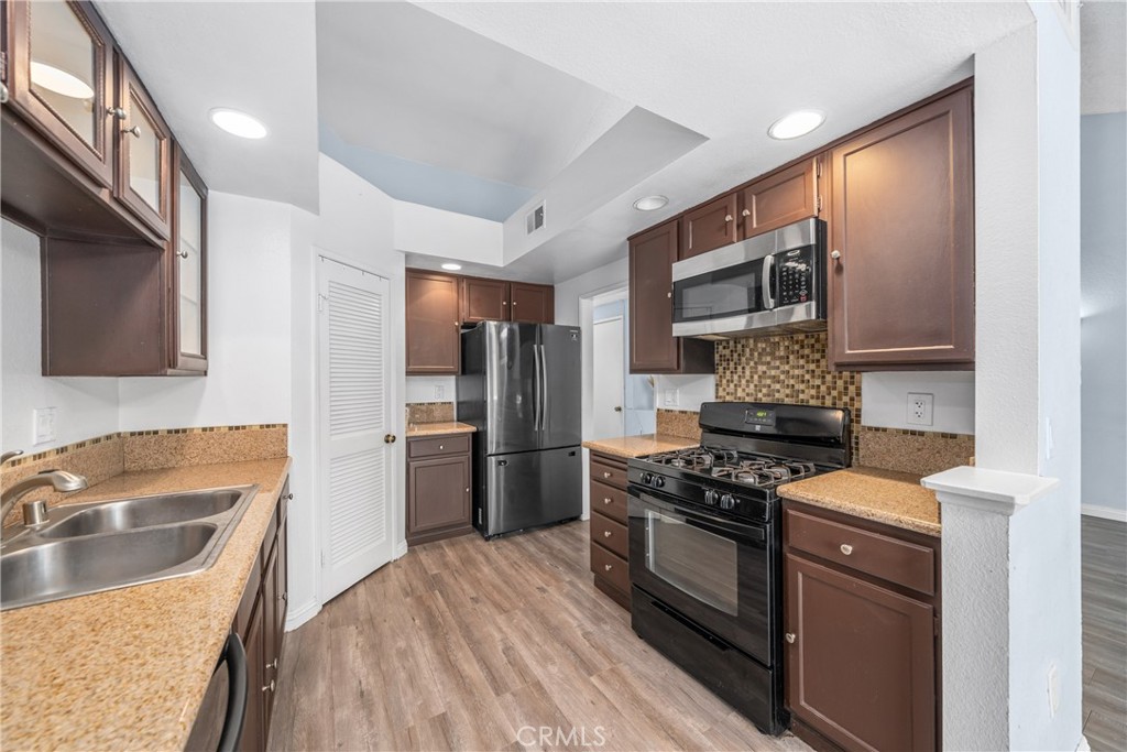 4900 North Grand Avenue, Unit 104 Covina, CA 91724 - Photo 10 of 27 a kitchen with stainless steel appliances a refrigerator a sink a stove a microwave and island