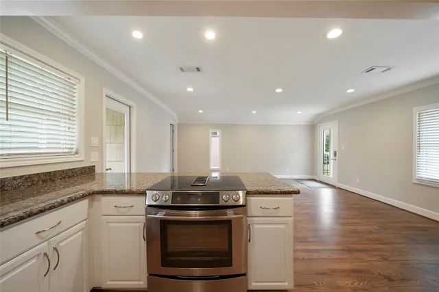 a large kitchen with granite countertop a large counter top stainless steel appliances and windows