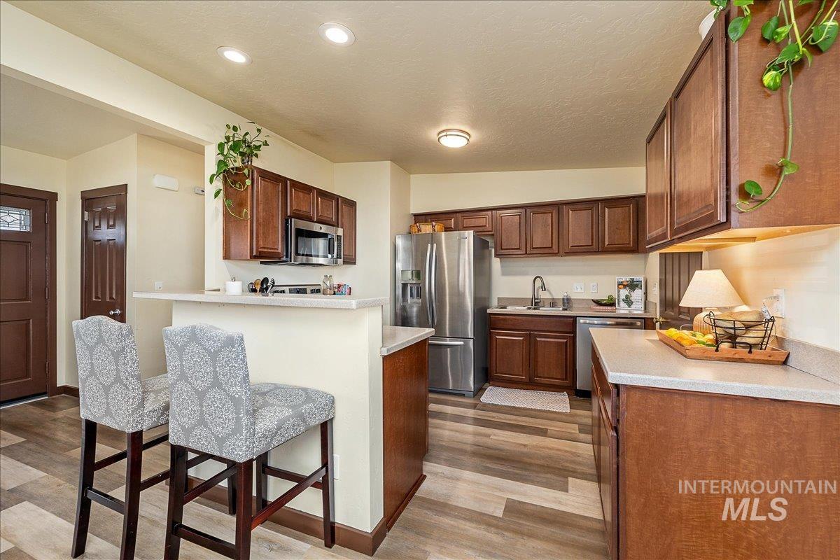 1910 Lemhi Street Boise, ID 83705 - Photo 29 of 41 Kitchen with stainless steel appliances, light countertops, a breakfast bar, light wood-style floors, and a textured ceiling
