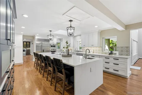 a kitchen with stainless steel appliances kitchen island granite countertop a table chairs in it and white cabinets