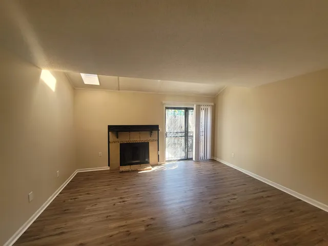 an empty room with wooden floor fireplace and windows