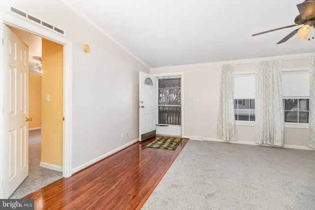 a view of an empty room with wooden floor and a window
