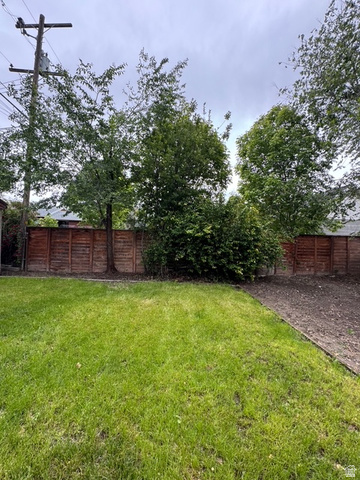 189 West Center Street Midvale, UT 84047 - Photo 51 of 64 Expansive backyard featuring a large grassy area, a perimeter fence, and mature trees providing natural screening