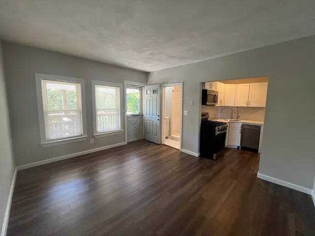 an empty room with windows a fireplace and wooden floor