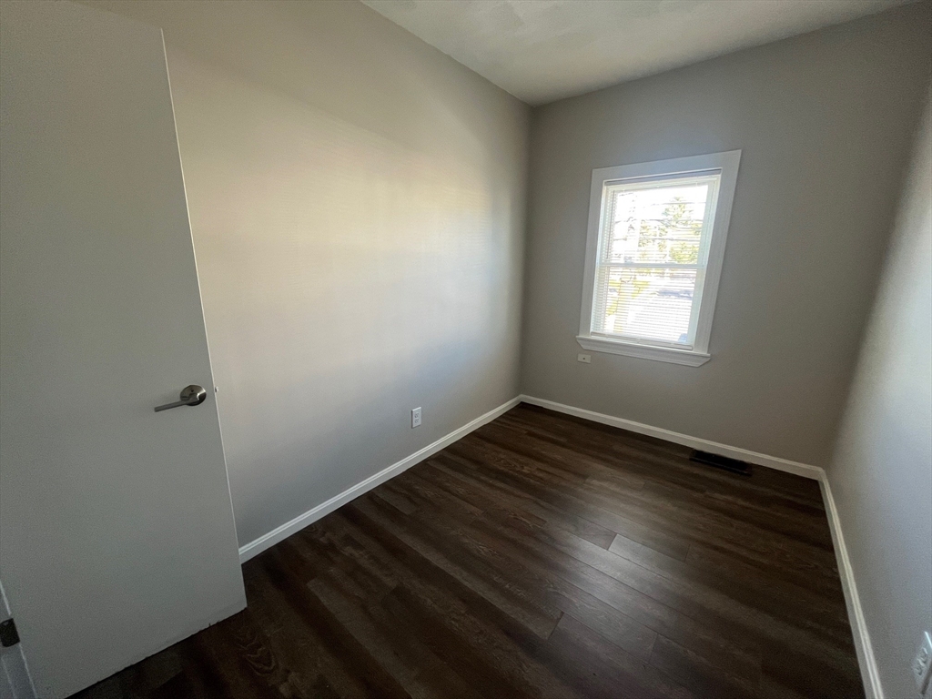 268 River Street, Unit 2 Waltham, MA 02453 - Photo 7 of 9 an empty room with wooden floor and windows