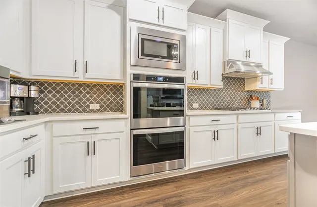 a kitchen with a refrigerator a sink and wooden floor