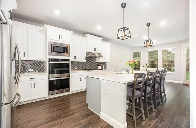 a kitchen with stainless steel appliances kitchen island granite countertop a white stove top oven and a chandelier