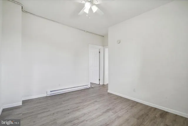 an empty room with wooden floor and fan