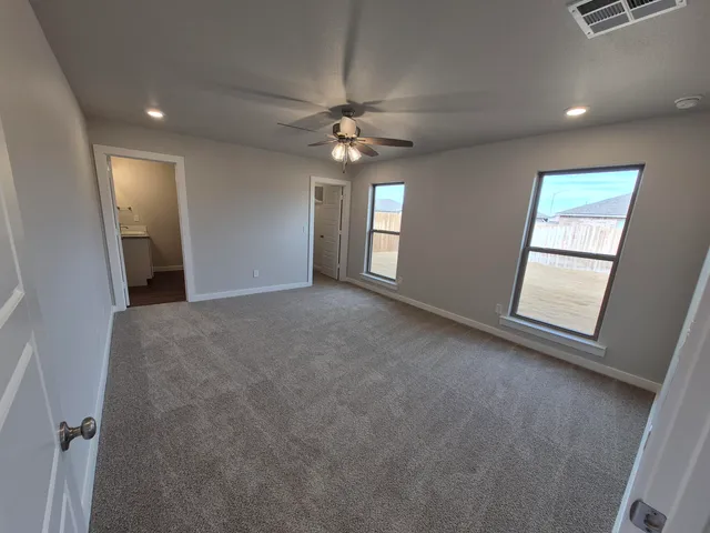 an empty room with windows and fan