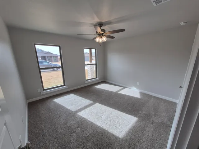an empty room with windows and fan