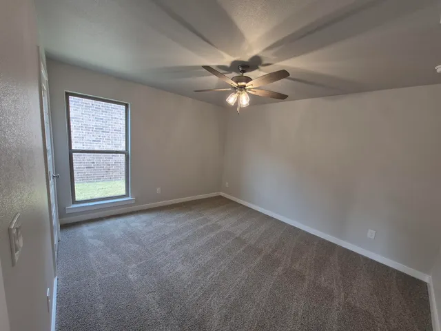 an empty room with a window and a fan
