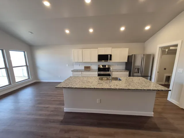 a view of a kitchen with granite countertop a stove and a sink