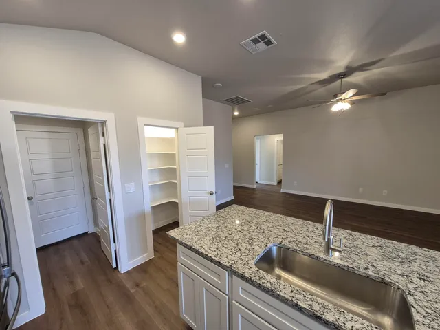 a kitchen with granite countertop a sink and refrigerator