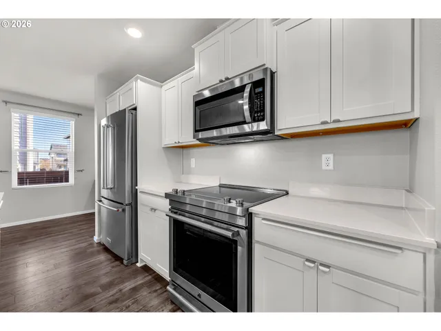 a kitchen with stainless steel appliances white cabinets and a stove top oven