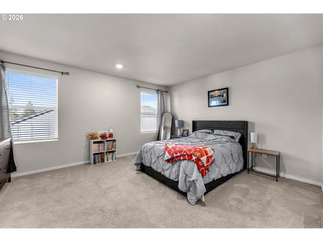 a bedroom with a bed painting on wall and windows
