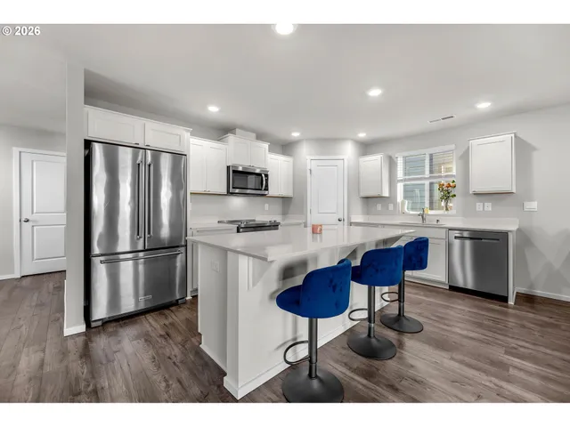 a kitchen with stainless steel appliances a refrigerator a stove a sink a dining table and chairs