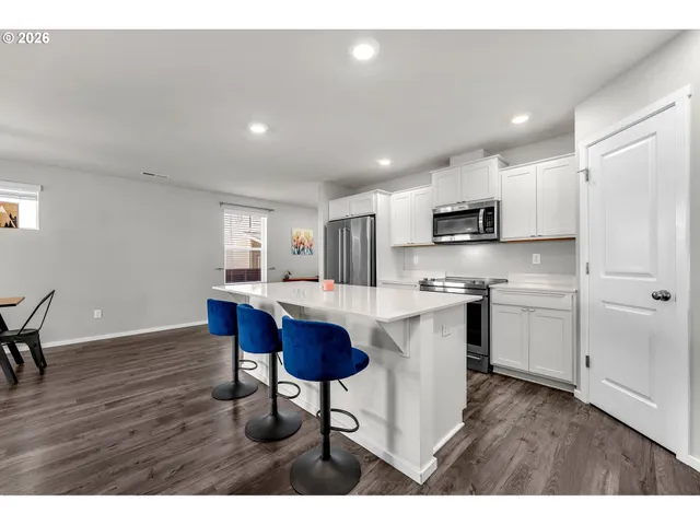 a kitchen with stainless steel appliances granite countertop a sink a stove a refrigerator cabinets and a dining table