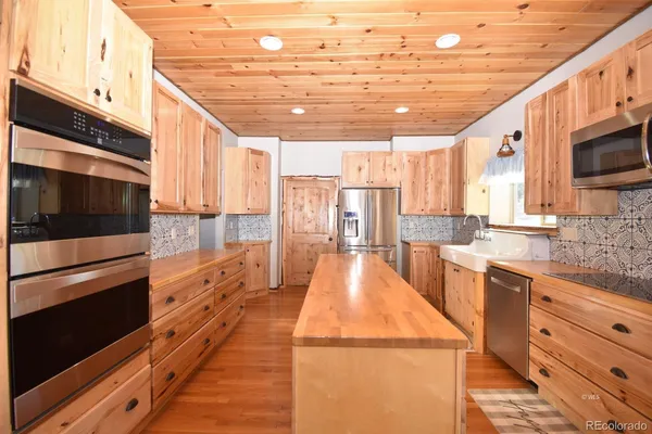 a large kitchen with stainless steel appliances kitchen island granite countertop a large stove a sink and a microwave