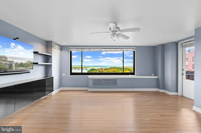 a view of an empty room with a window and wooden floor