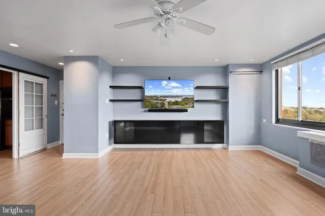 a view of an empty room with a window and wooden floor