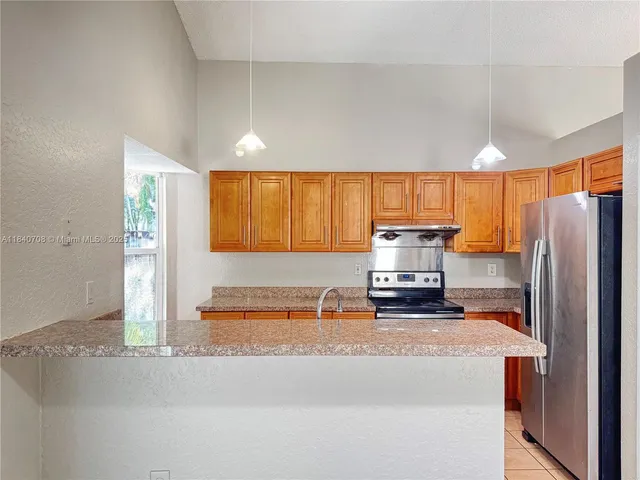 a kitchen with stainless steel appliances granite countertop a refrigerator a stove and a sink