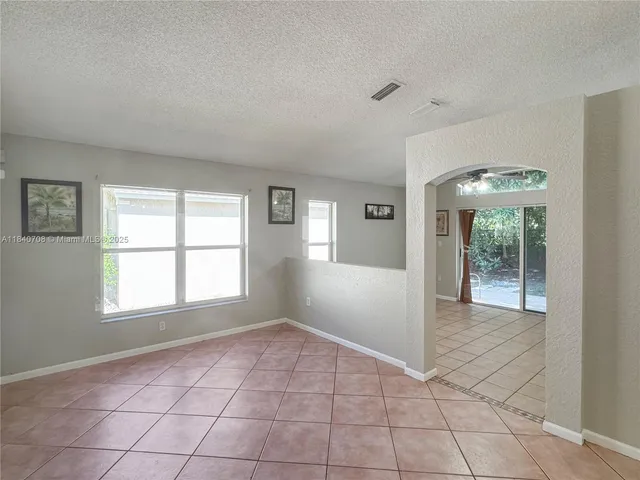 a view of an empty room with window and chandelier fan