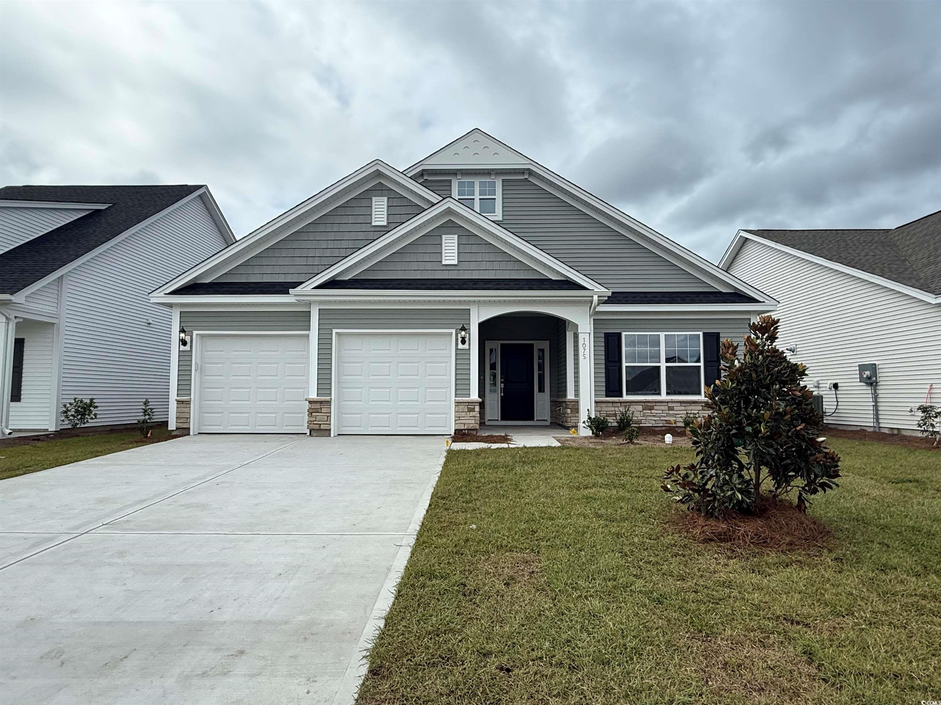 Craftsman house featuring driveway, a garage, a front lawn, and stone siding