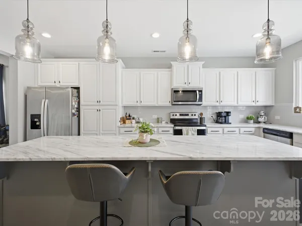 a kitchen with kitchen island granite countertop a sink a counter top space appliances and cabinets