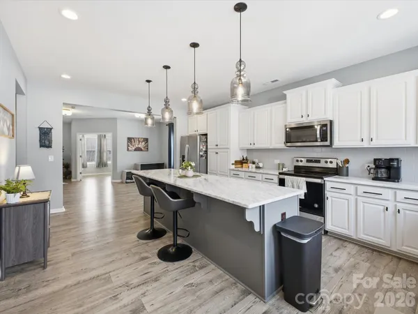 a large kitchen with kitchen island a island a sink a stove and a wooden floors