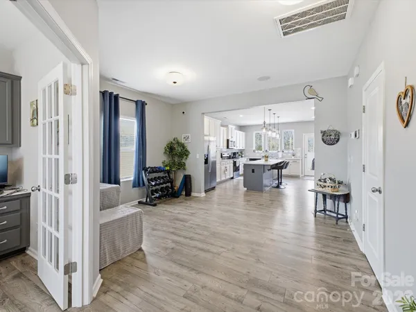 a large kitchen with stainless steel appliances kitchen island granite countertop a sink dishwasher a stove a dining table and chairs with wooden floor