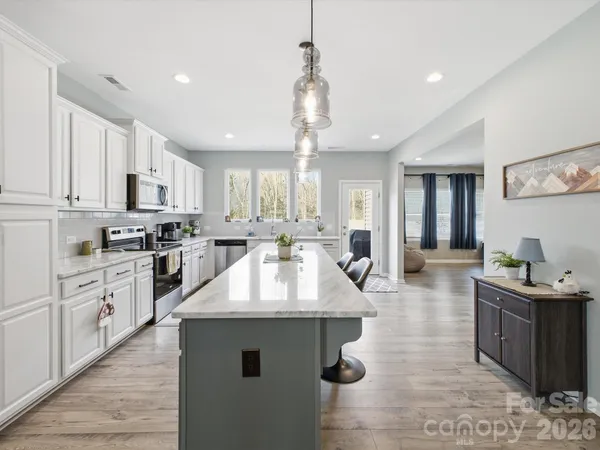 a kitchen with stainless steel appliances granite countertop a sink refrigerator a stove a microwave and white cabinets