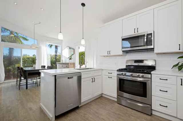 a kitchen with a stove a sink and a wooden floor
