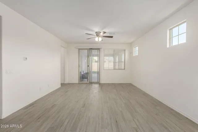 an empty room with wooden floor and windows