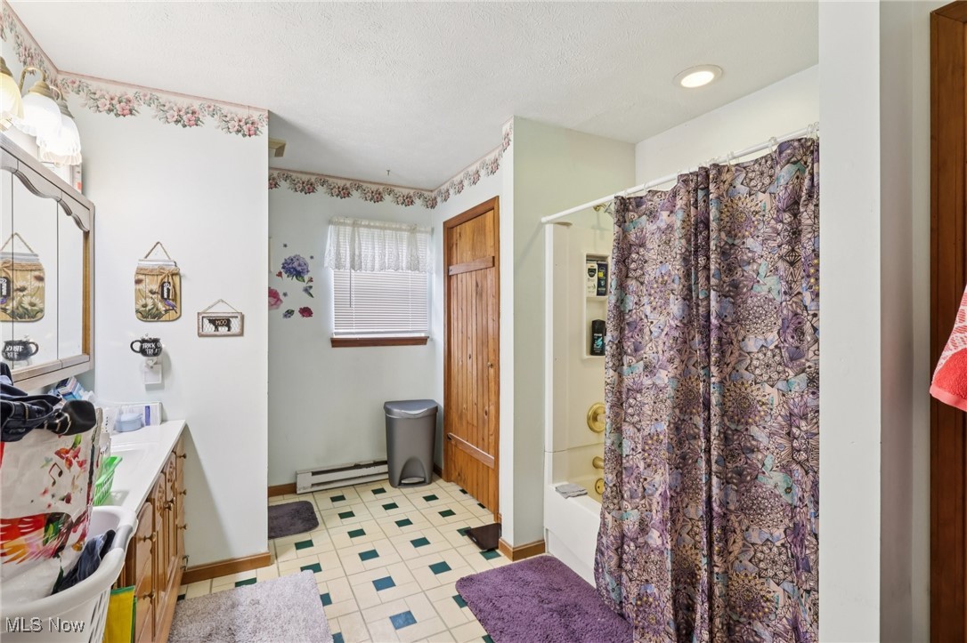 6370 Trumbull Road Geneva, OH 44041 - Photo 24 of 50 Bathroom featuring vanity, shower / bath combo with shower curtain, a baseboard radiator, light tile patterned floors, and a textured ceiling