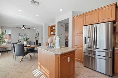 a kitchen with stainless steel appliances granite countertop a refrigerator a sink a stove a dining table and chairs