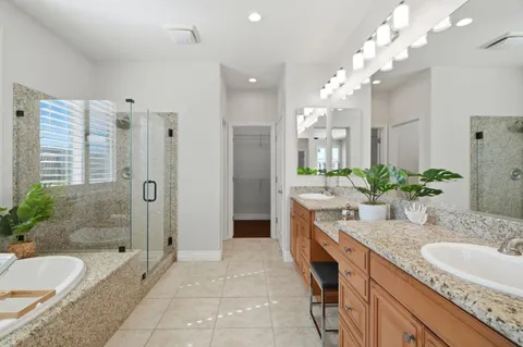 a bathroom with a granite countertop double vanity sink mirror bathtub and shower