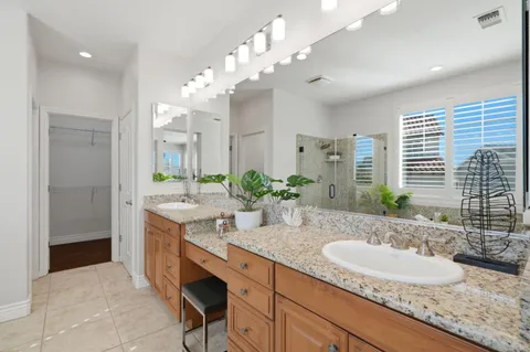 a bathroom with double vanity sinks a vanity a mirror and a shower