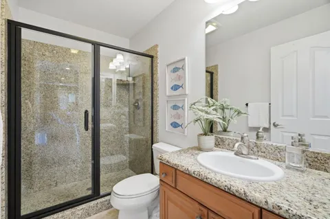 a bathroom with a granite countertop sink toilet and shower
