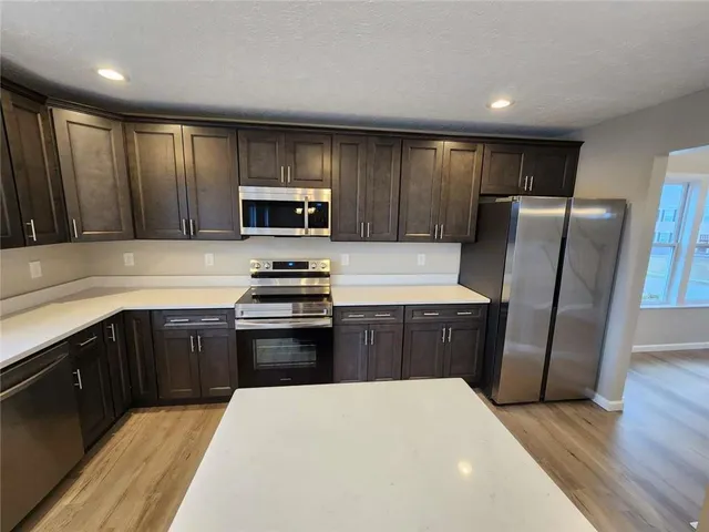 a kitchen with granite countertop a refrigerator stove top oven and sink