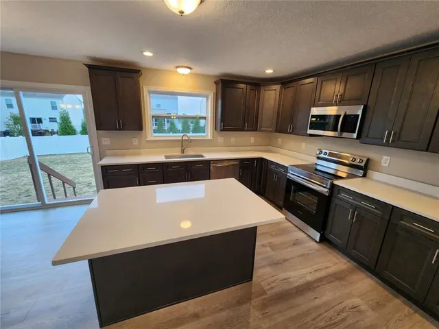 a kitchen with stainless steel appliances a stove a sink a microwave a refrigerator and cabinets