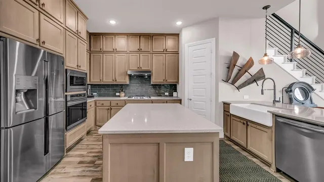 a kitchen with kitchen island granite countertop a sink stainless steel appliances and cabinets