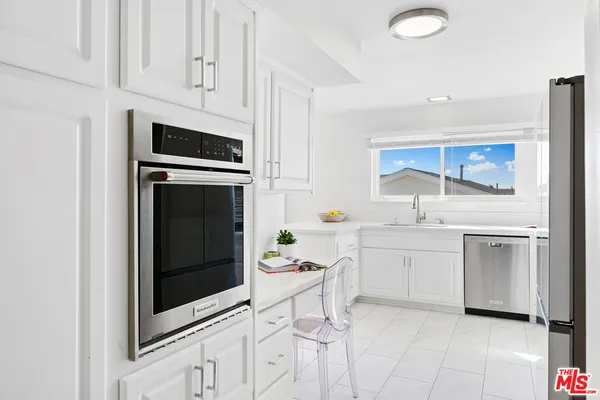 a kitchen with white cabinets and appliances