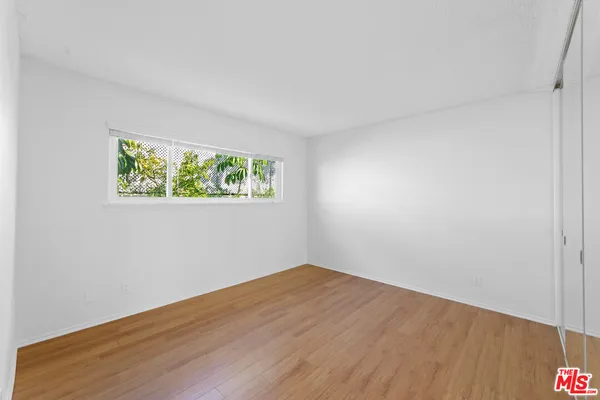 an empty room with wooden floor and window