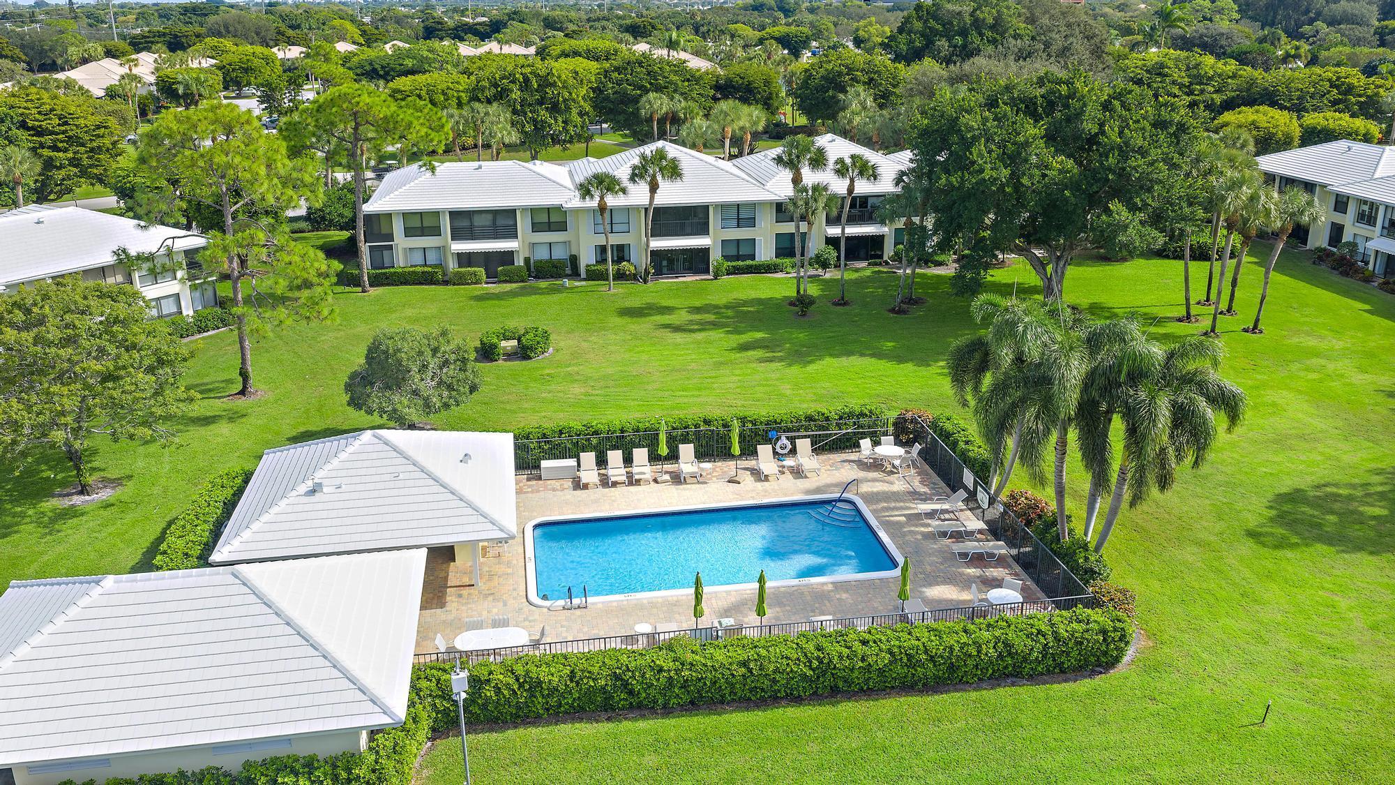 3693 Quail Ridge Drive, Unit BOBWHITE B Boynton Beach, FL 33436 - Photo 24 of 39 a view of a white house with a yard table and chairs