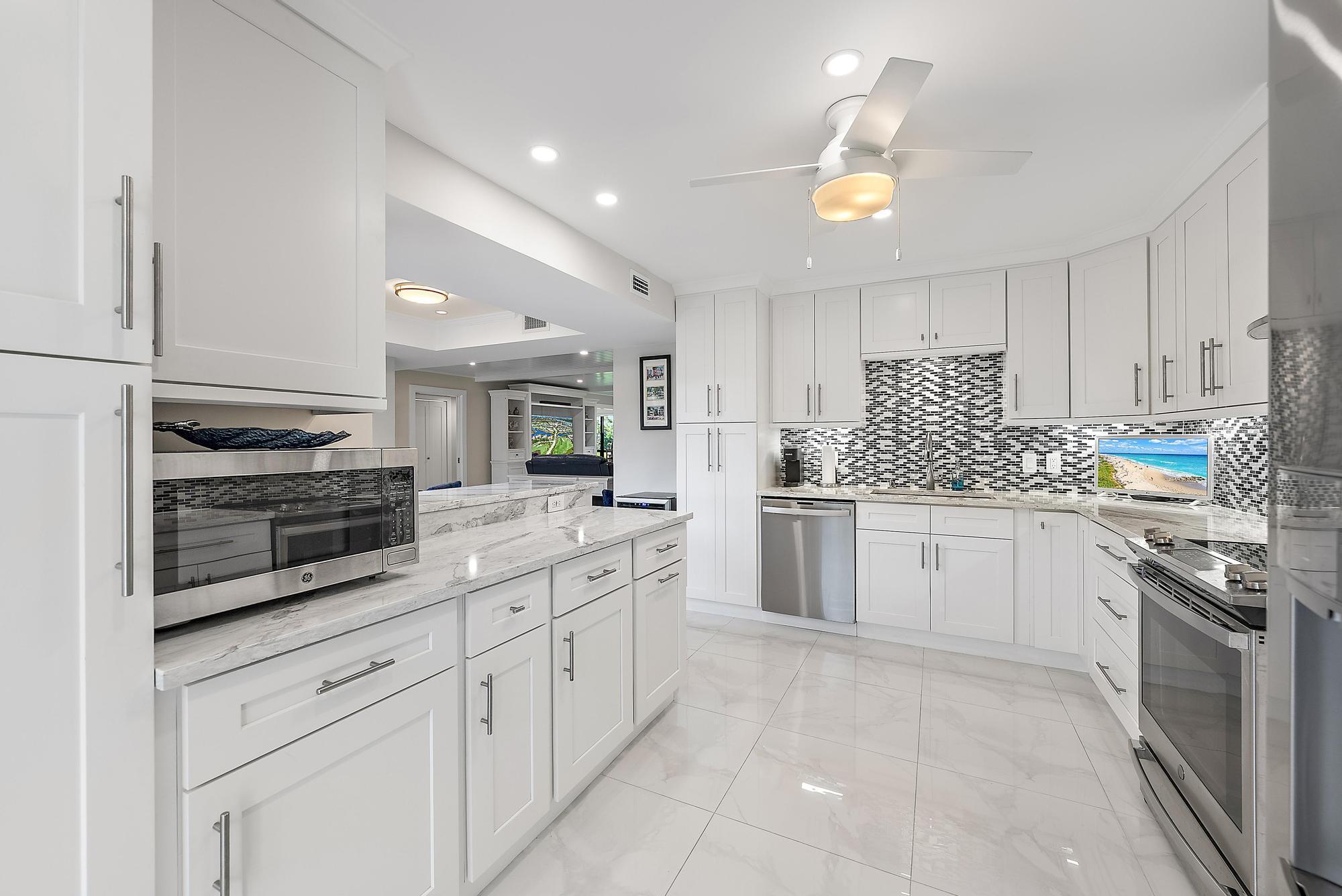 3693 Quail Ridge Drive, Unit BOBWHITE B Boynton Beach, FL 33436 - Photo 9 of 39 a kitchen with granite countertop white cabinets and white stainless steel appliances