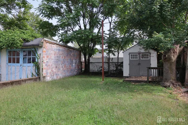 a backyard of a house with plants and large tree