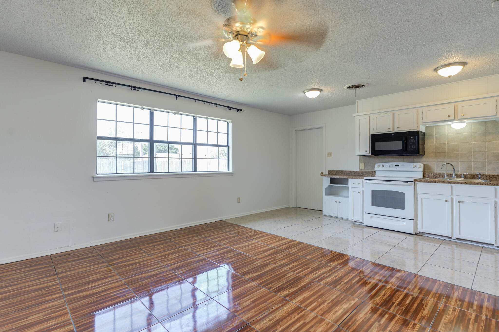 1313 Adrian Street Lubbock, TX 79403 - Photo 8 of 26 a kitchen with granite countertop a stove a sink and a microwave