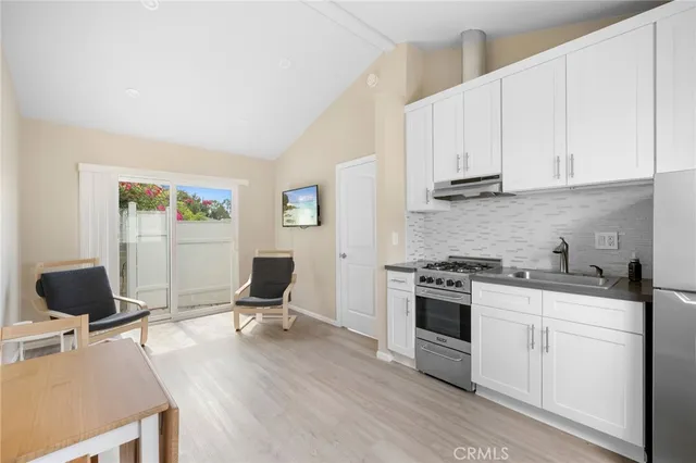 a kitchen with stainless steel appliances kitchen island granite countertop a stove top oven a sink a counter space and cabinets